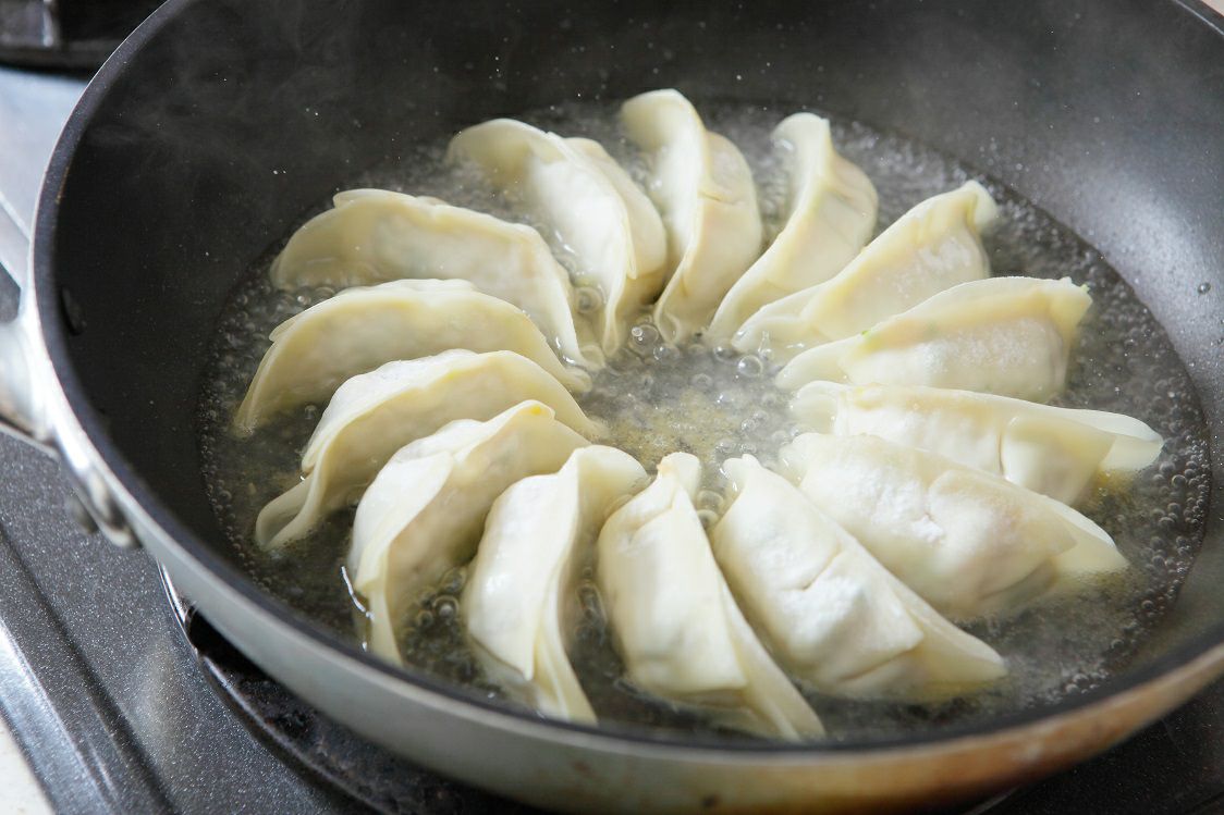 フライパンまたは鍋に「将軍餃子」と「しそ餃子」を並べ、焼き色がついている調理中の画像。人気2種類の餃子を同時に焼いている様子。