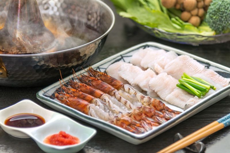 大分県産車海老と鱧のしゃぶしゃぶを調理し、温かい出汁と共に、食卓の皿に盛り付けた画像。冬のギフトやお歳暮に最適な、豪華な海鮮しゃぶしゃぶセット。