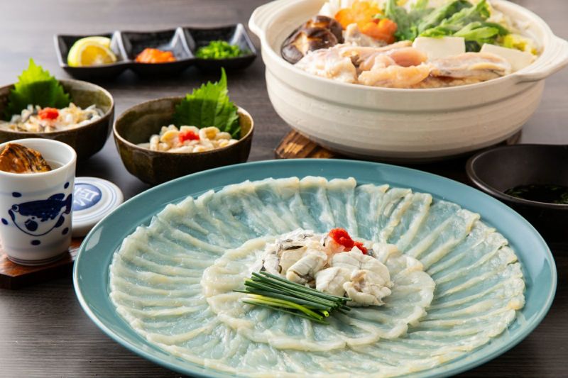 大分県産の高級魚「豊後とらふぐ」料理セットで楽しめる、てっさ（刺身）、てっちり（鍋）、ヒレ酒の豪華な食卓の盛り付け画像。ご贈答にも最適な大分のご当地ふぐセットを通販でお取り寄せ。