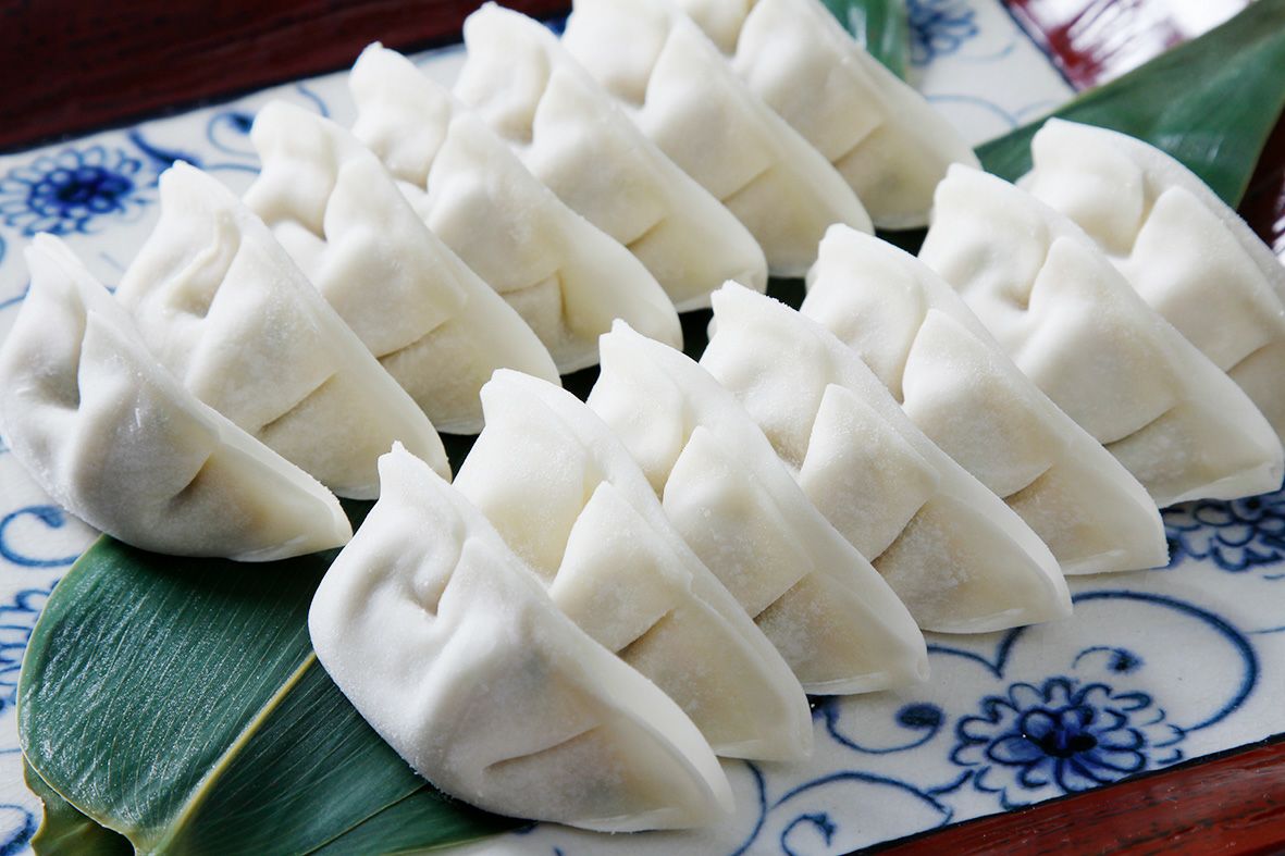 製麺メーカーならではの最高級の皮に包まれた、調理前の「将軍餃子」の真っ白な生餃子がトレーにきれいに並んだ画像。