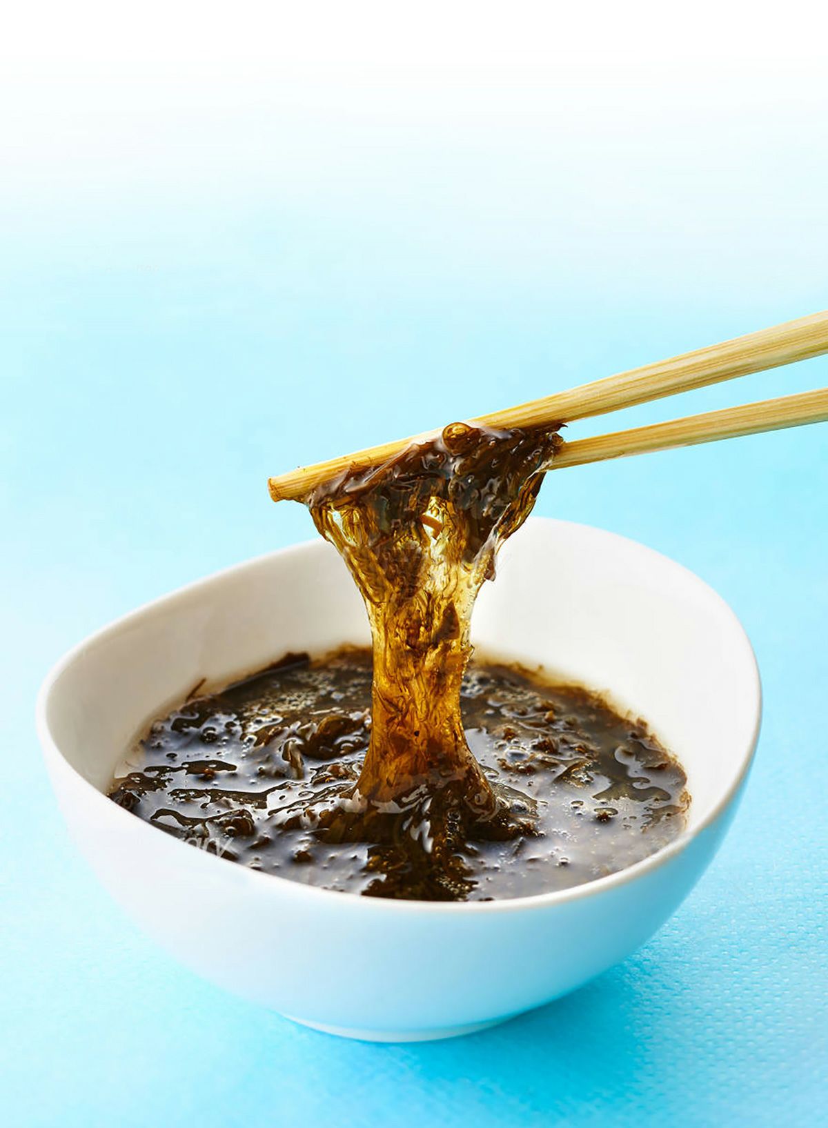 タレの具材として使用される、大分特産の「天然クロメ」を箸で持ち上げているアップ画像。クロメ特有の強い粘り気と、磯の風味を伝えるビジュアル。