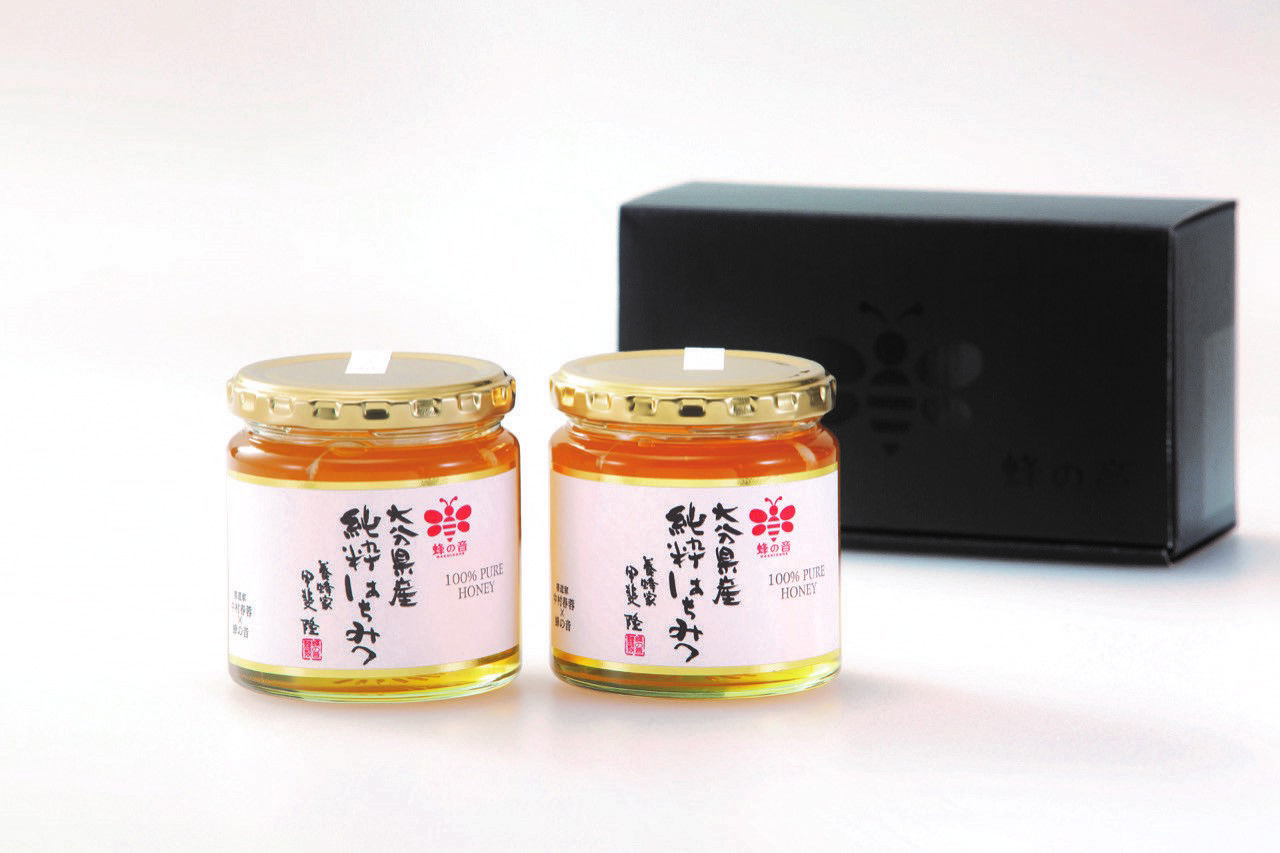 大分県で採蜜された「大分県百花はちみつ300g」の容器2本とギフトボックスを並べた画像。贈答やお返しに最適な、大分の四季の恵みを感じる純粋はちみつ。