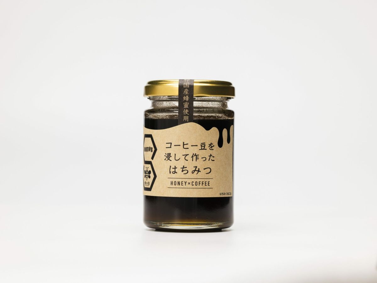 「DOUTOR(ドトール)」と「蜂の音」のコラボ商品「コーヒー豆を浸したはちみつ」の瓶単体画像。コーヒー豆の風味と国産蜂蜜の甘さが楽しめる、パンやヨーグルトに最適なはちみつ加工品。