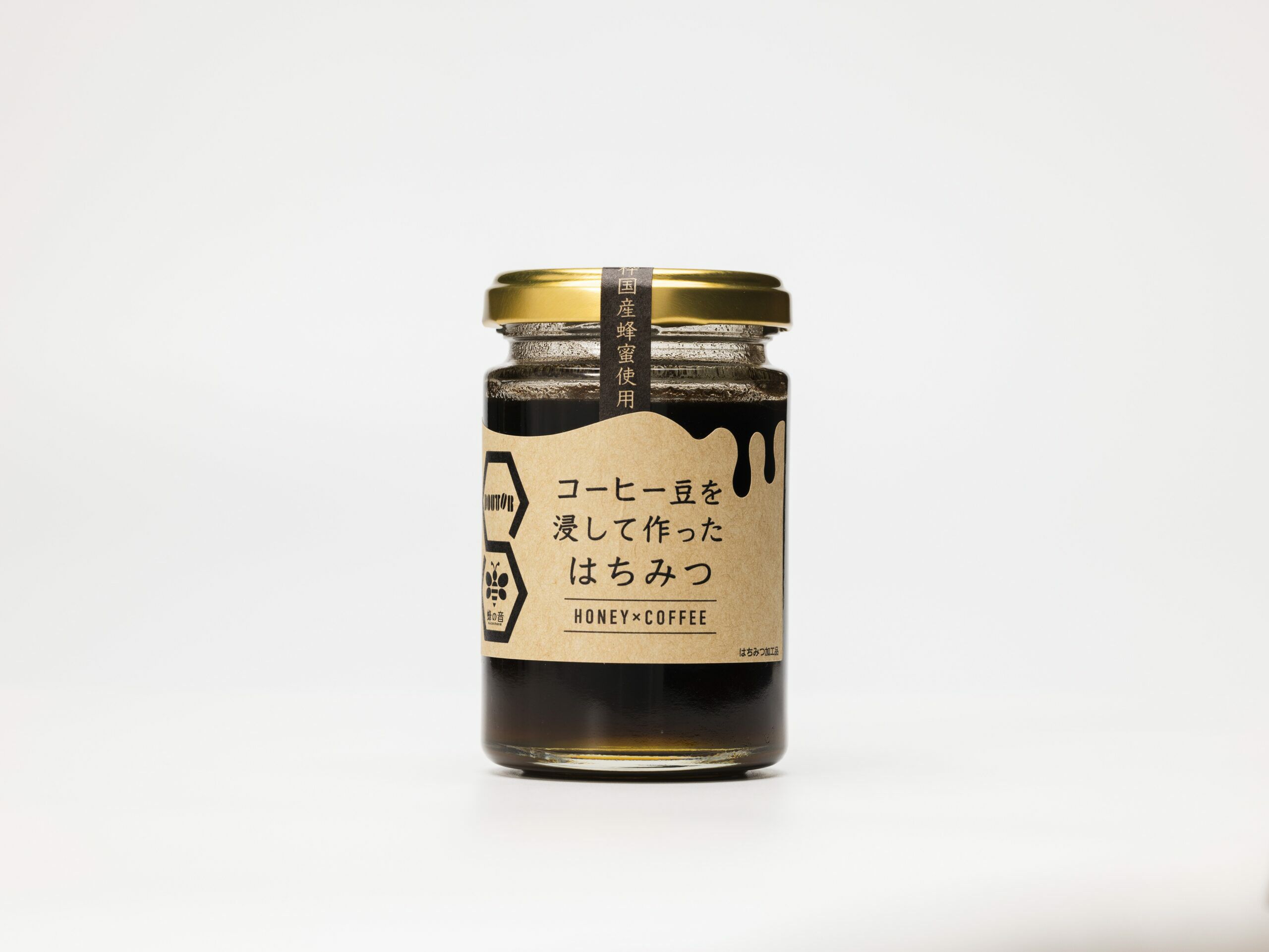 「DOUTOR(ドトール)」と「蜂の音」のコラボ商品「コーヒー豆を浸したはちみつ」の瓶単体画像。コーヒー豆の風味と国産蜂蜜の甘さが楽しめる、パンやヨーグルトに最適なはちみつ加工品。