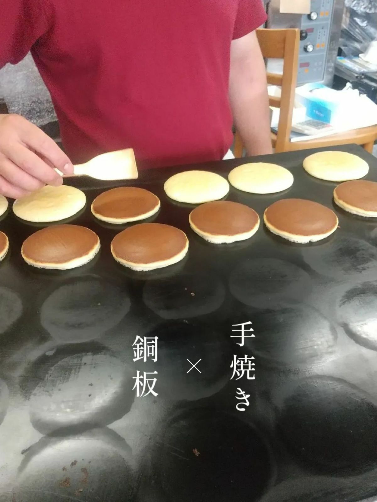 和菓子職人の父子が、銅板（鉄板）でどら焼きの生地を一枚一枚手焼きしている製造工程の画像。地元の卵と地酒を隠し味に使った、しっとりとした生地へのこだわり。