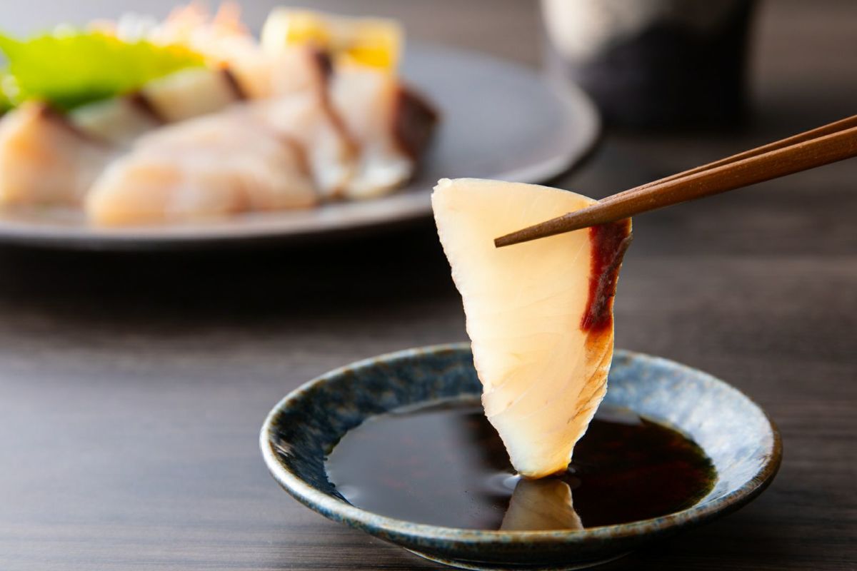 新鮮な関ぶりの刺身（関冷刺）を醤油につけているアップ画像。身の締まりと脂の乗りが伝わる、大分からのお取り寄せ海鮮。