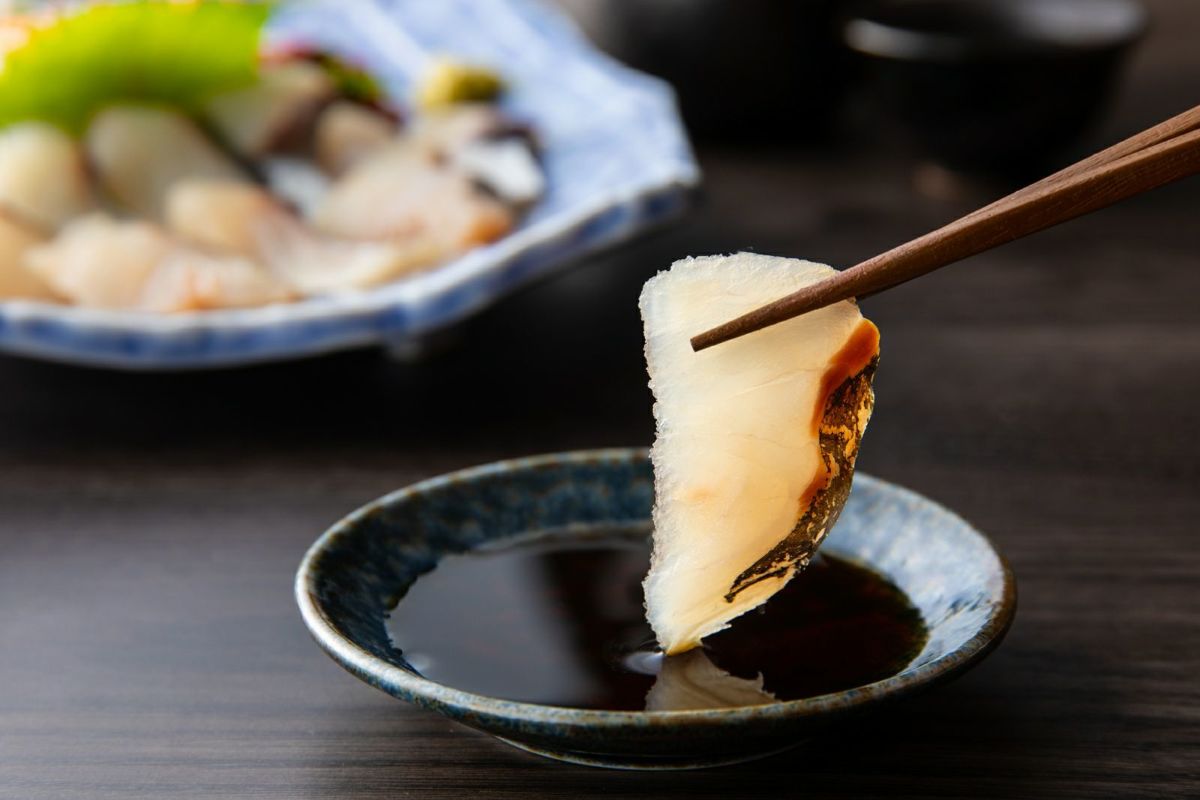 新鮮な関あじの刺身（関冷刺）を醤油につけているアップ画像。身の締まりや脂の乗りが伝わる、大分からのお取り寄せ海鮮。