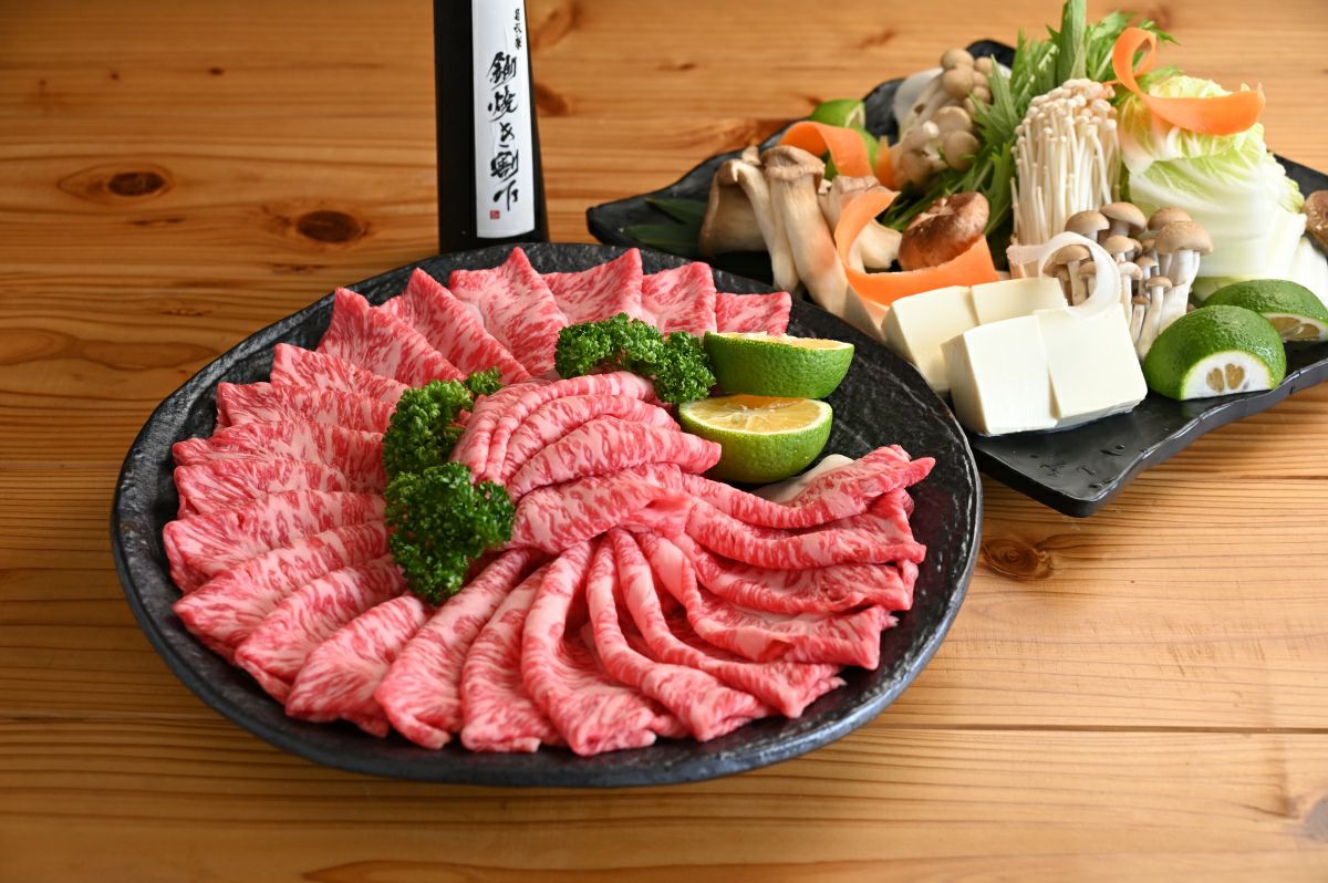 大分県のブランド牛「おおいた和牛」と旬の野菜を皿に盛り付けた、すき焼きセットの調理前画像。特製割り下も付いており、ご自宅で豪華なすき焼きを楽しめる。
