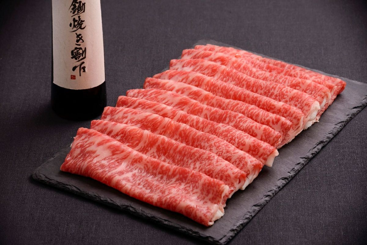 大分県のブランド牛「おおいた和牛」（すき焼き用）と、特製ダレで味付けされた「国産ホルモン」を大皿に盛り付けた調理前の画像。大分の贅沢な肉料理を一度に楽しめるセット