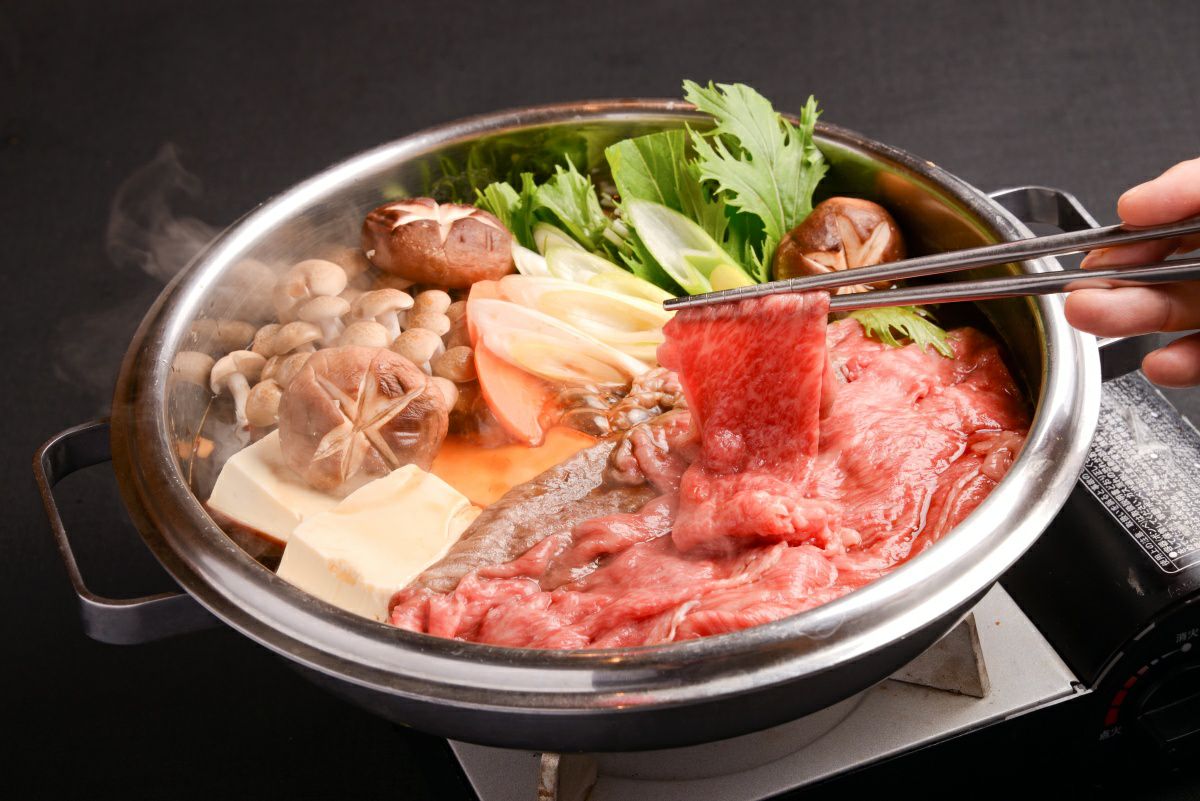 大分県のブランド牛「おおいた和牛」のすき焼き肉と野菜を鍋で煮込んでいる調理中の画像。美しい霜降りの和牛と甘い割下の香りが伝わる、食卓を囲むのに最適なすき焼き。