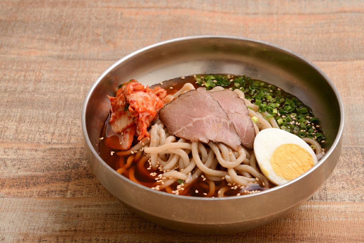 大分・別府のご当地グルメ「別府冷麺」の調理後の盛り付け画像。牛骨ベースのあっさりとした冷たいスープ、コシのある太麺、チャーシューやキムチなどがバランス良く盛り付けられた完成品。